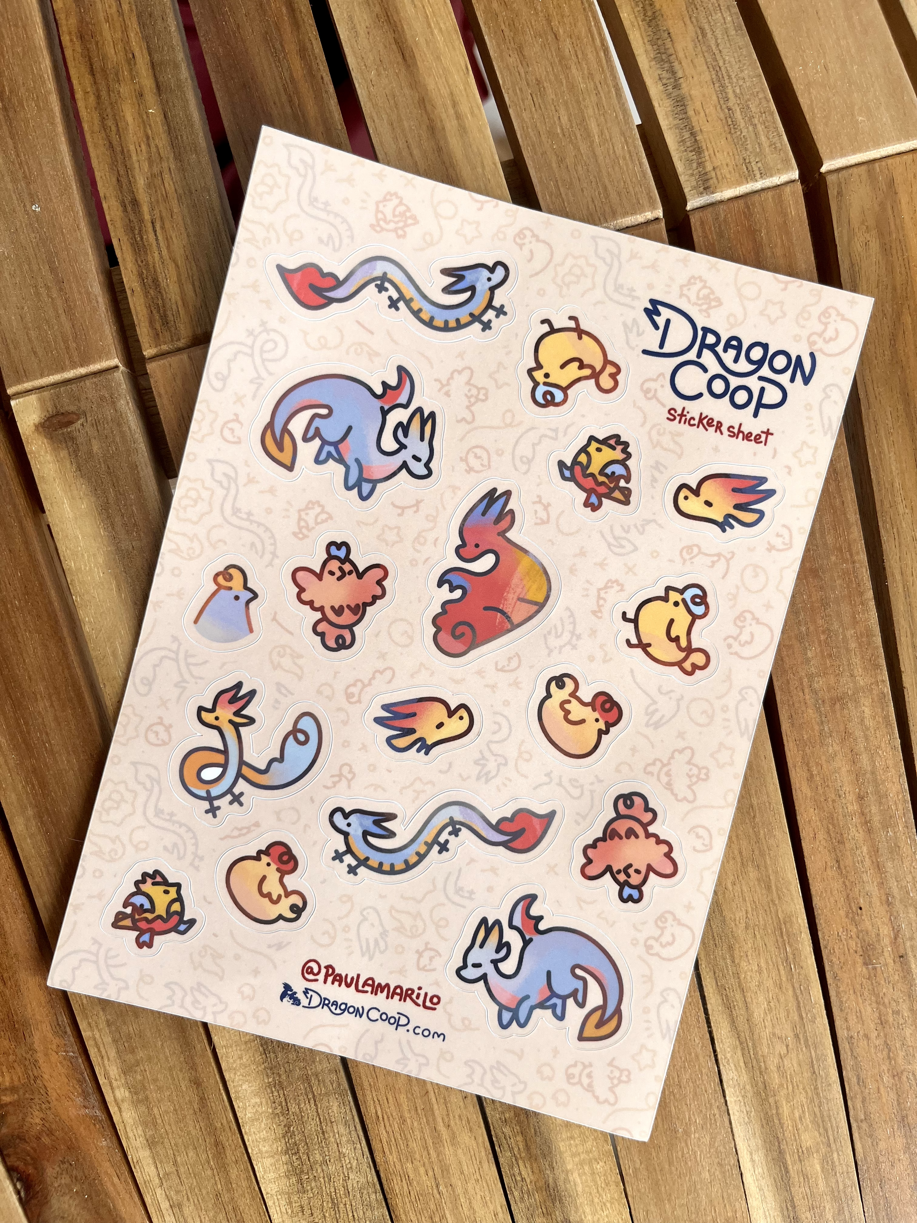 A sheet of colorful dragon and chicken stickers from Dragon Coop on a wooden surface.
